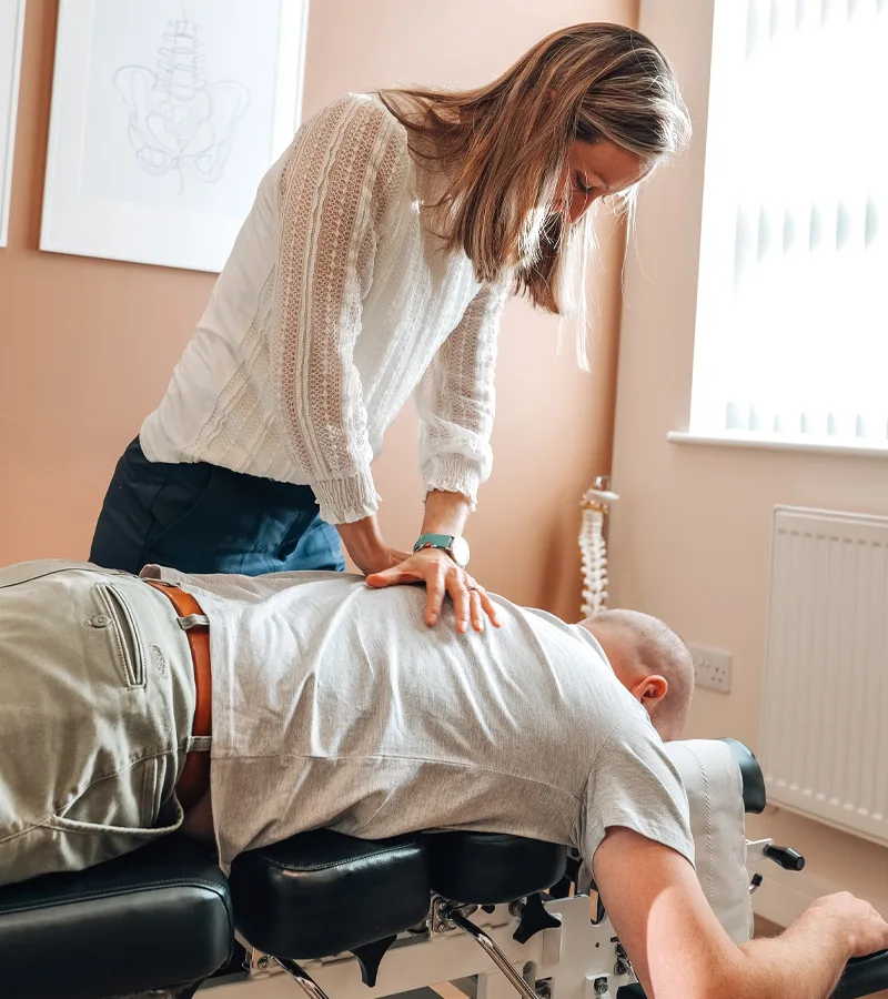 Chiropractor adjusting the mid back of a patient lying face down