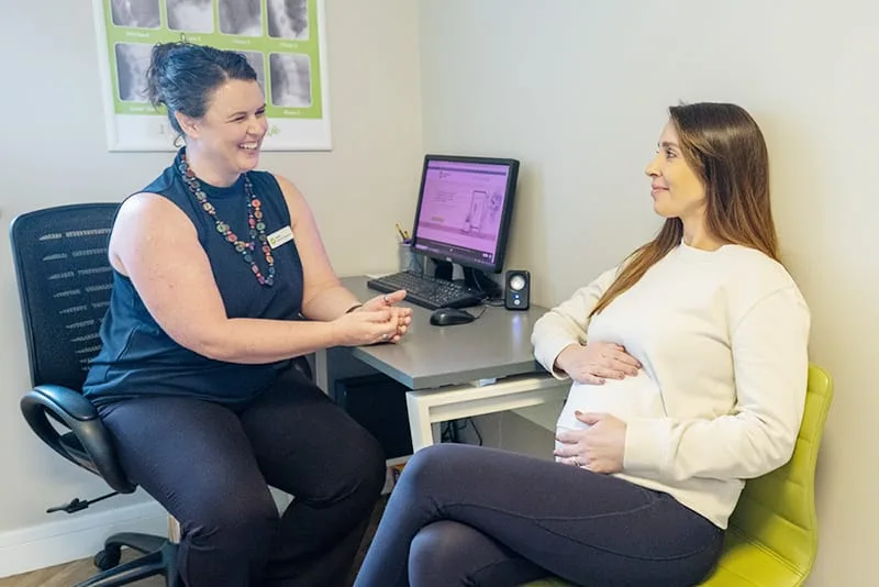 Pregnant patient talking with a clinic team member at a desk
